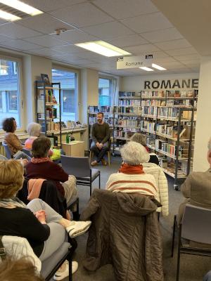 Lesung in der Bibliothek mit einem Leser und Besucherinnen